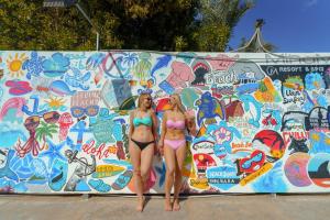 two women in bikinis standing next to a wall covered in graffiti at MinaMark Beach Resort for Families and Couples Only in Hurghada