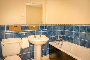 a blue tiled bathroom with a toilet and a sink at Sailor's Rest - modern flat with water views in Pevensey +16 photos