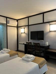 a hotel room with two beds and a desk and a television at Orbita hotel Shymkent in Shymkent