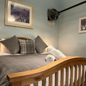 een slaapkamer met een houten bed met kussens bij Hafan Cottage at Bryn Llys in Bethesda