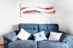 a blue couch with three pillows sitting under a painting at Modern Beach & Spa in Torrevieja