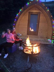 2 personnes assises devant une tente avec un feu dans l'établissement East Coast Adventure Centre Glamping, à Rostrevor