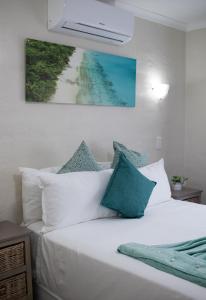 Hillas Ridge Guesthouse في فاندربيجلبارك: سرير بمخدات بيضاء ولوحة على الحائط