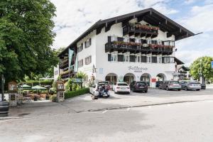 un grande edificio bianco con auto parcheggiate in un parcheggio di Hotel Bellevue a Bad Wiessee