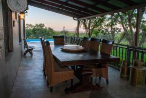 einen Holztisch und Stühle auf einer Veranda mit einer Uhr in der Unterkunft Casa con Vistas in Polokwane