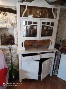 a white hutch with glass doors in a kitchen at Hobbit house lubenice in Lubenice +8 photos