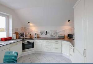 a kitchen with white cabinets and a large window at Schöne ruhige Ferienwohnung für die ganze Familie in Risum-Lindholm