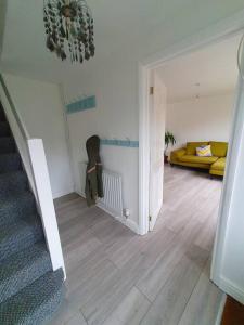 a living room with a staircase and a yellow couch at Rabbit Haven - 4 minutes from Bicester Village! in Bicester