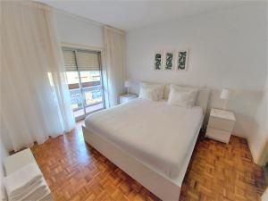 a white bedroom with a large bed and a window at Braga centro - apartamento espaçoso e confortável - Todas as comodidades in Braga