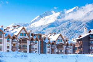 a resort with snow covered mountains in the background at Emerald Buddha Apartment in Bansko