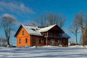 uma casa laranja com um telhado preto na neve em Ķestermuiža em Alūksne