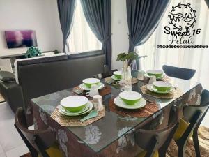 a dining room table with green and white dishes on it at Sweet 16 Pelali Homestay Pengerang (Wifi/Netflix) in Pengerang