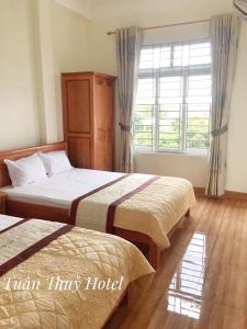 Habitación de hotel con 2 camas y ventana en Tuân Thuỷ hotel đảo Quan Lạn en Quan Lạn