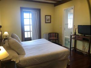 una camera da letto con un letto bianco e una televisione di Casa Grande de Fuentemayor a Silleda