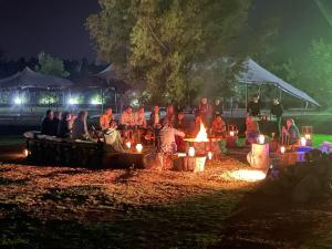 Un gruppo di persone sedute intorno al fuoco di notte di La Posada Multiespacios a Dique Luján