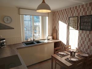 a kitchen with a sink and a table and a window at La Porte Rose in Rochesson