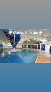 a swimming pool in a mall with a sign that reads coastal retreat at Coastal retreats, Beech rise, primrose valley in Filey