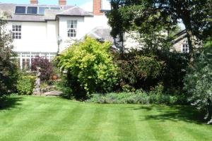 a yard of a house with a green lawn at Kwerky Cottage in North Lydbury