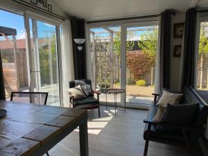 a living room with a table and chairs and sliding glass doors at Coast Holiday Appartements in Dirkshorn