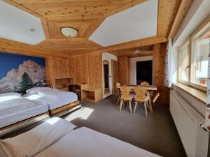 a bedroom with two beds and a table and chairs at Hotel Borest in Colfosco