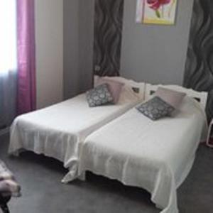 2 łóżka w pokoju z białą pościelą i poduszkami w obiekcie Jolie maison atypique à Montrichard w mieście Montrichard