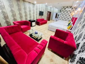 ein Wohnzimmer mit roten Möbeln und einem Bett in der Unterkunft Hotel Serena Palace in Multan