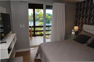 a bedroom with a bed and a door to a balcony at Mirante da Figueira - Suítes para temporada in Angra dos Reis