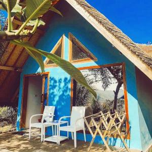 una casa con 2 sillas blancas y una pared azul en Blue Monkey Retreat Areguling Lombok, en Kuta Lombok