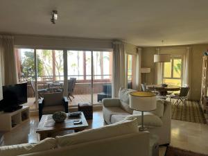 Una sala de estar con muebles blancos y una gran ventana. en Apartamento Puerto de Sotogrande con vistas al mar, en Sotogrande