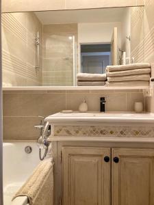 a bathroom with a sink and a mirror and a tub at Les Restanques coquelicot vue mer in Grimaud