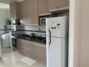 eine Küche mit einem weißen Kühlschrank und einem Herd in der Unterkunft SOLAMAR - PRAIA Das TONINHAS in Ubatuba