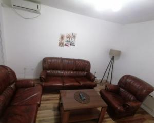 a living room with brown leather couches and a table at ANI Apartments Banja Luka in Banja Luka
