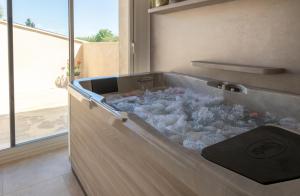 a bath tub filled with water in a room with a window at Mas des Tourterelles in Jonquières