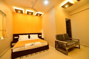 a bedroom with a bed and a chair at GRACE RESIDENCY in Tirūr