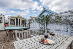 a picnic table with a plate of fruit and wine glasses at Sandy Lane Cottage in Reydon in Southwold