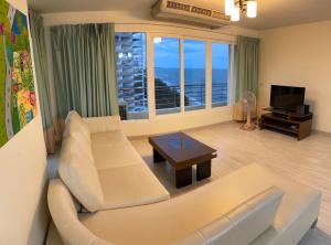 a living room with a white couch and a television at Beach Condo in Cha Am