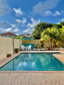 una piscina en un patio trasero con mesa y sillas en Entire 4BDR Vistalmar Villa with Private Pool en Oranjestad