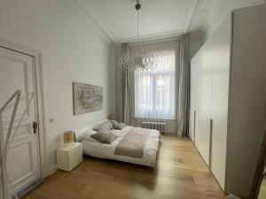 a white bedroom with a bed and a window at Apartment in trendy Chatelain center Brussels area Little Garden Internet wifi in Brussels
