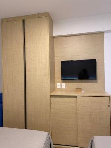 a bedroom with a flat screen tv on a wall at Flat em Guarajuba, Paraíso dos Coqueiros in Guarajuba
