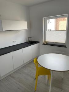 a kitchen with a white table and a yellow chair at Gästehaus Emma in Niederkassel