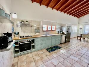 uma grande cozinha com armários verdes e piso em azulejo em Entire 4BDR Vistalmar Villa with Private Pool em Oranjestad