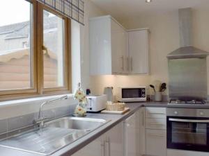 cocina con armarios blancos, fregadero y ventana en Rosebank Cottage en Lancaster
