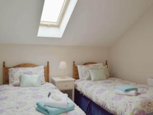two twin beds in a room with a window at Rosebank Cottage in Lancaster