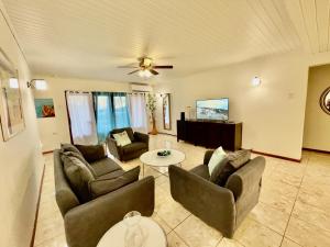 a living room with couches and a ceiling fan at Entire 4BDR Vistalmar Villa with Private Pool in Oranjestad