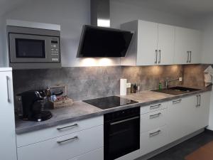 a kitchen with white cabinets and a sink and a microwave at Relax 2 in Bad Wildbad