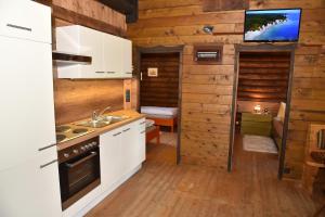 a kitchen with white cabinets and a tv on the wall at Berghütte Ahrntal in San Giovanni in Val Aurina