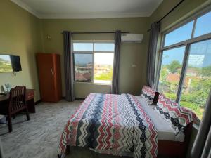 sypialnia z łóżkiem i dużym oknem w obiekcie PHYLLEN HOTEL w mieście Tanga