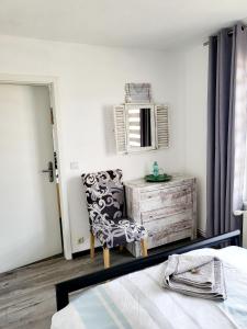 a bedroom with a bed and a chair and a mirror at Heimathafen Ückeritz in Ueckeritz +4 photos