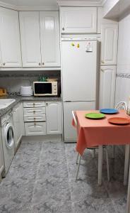 a kitchen with a table and a white refrigerator at Apartamento Armonía:céntrico, tranquilo y acogedor in Elda