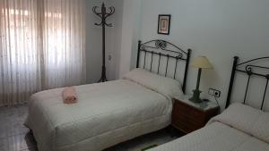 1 dormitorio con 2 camas y mesa con lámpara en Apartamento Armonía:céntrico, tranquilo y acogedor, en Elda